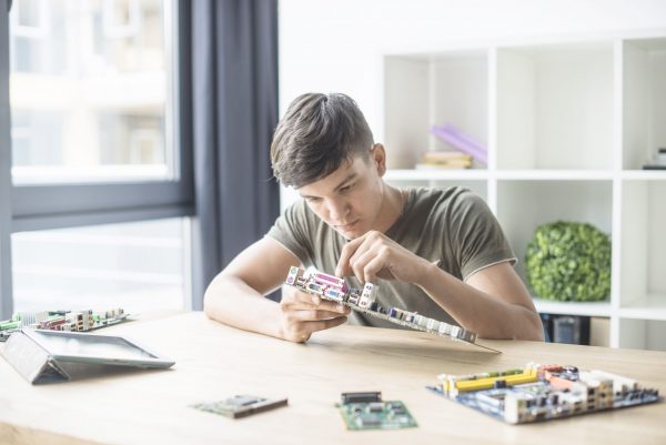 Парень-подросток ремонтирует компьютер